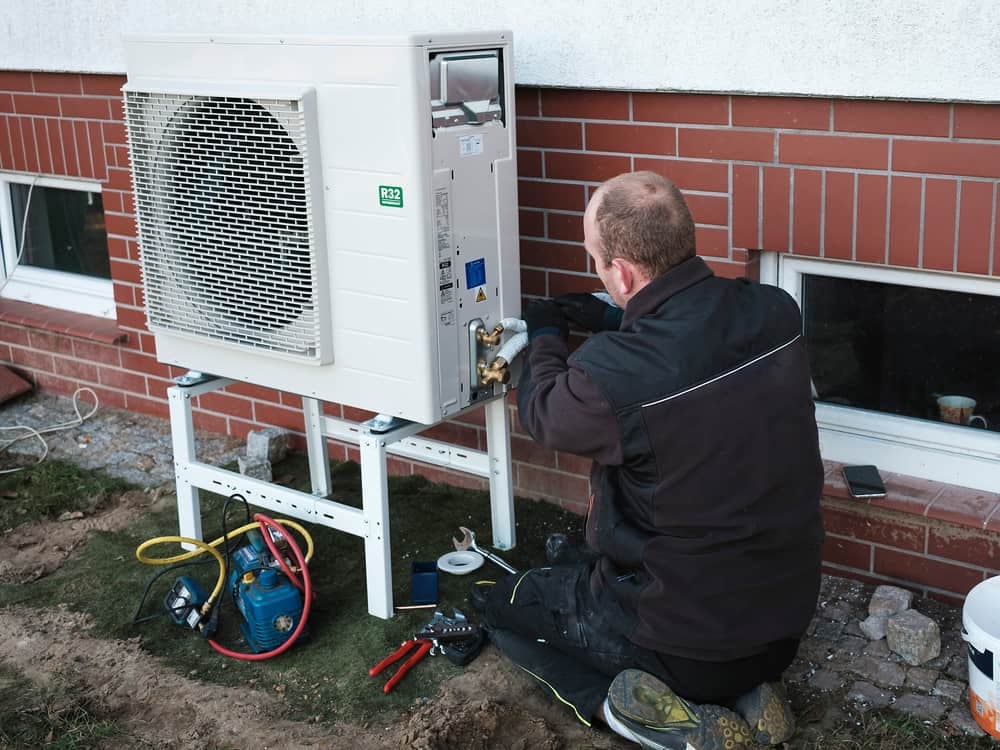 a man is repairing a heat pump in a home's yard in Vancouver