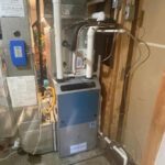 Technician from Vanhat Services performing annual furnace maintenance on a home HVAC system.