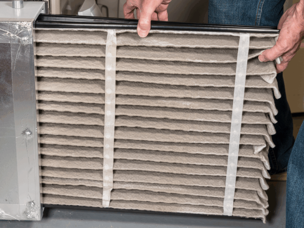 Technician changing a dirty furnace air filter to improve efficiency