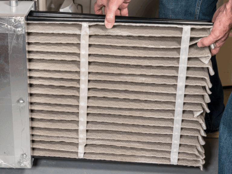 Technician changing a dirty furnace air filter to improve efficiency